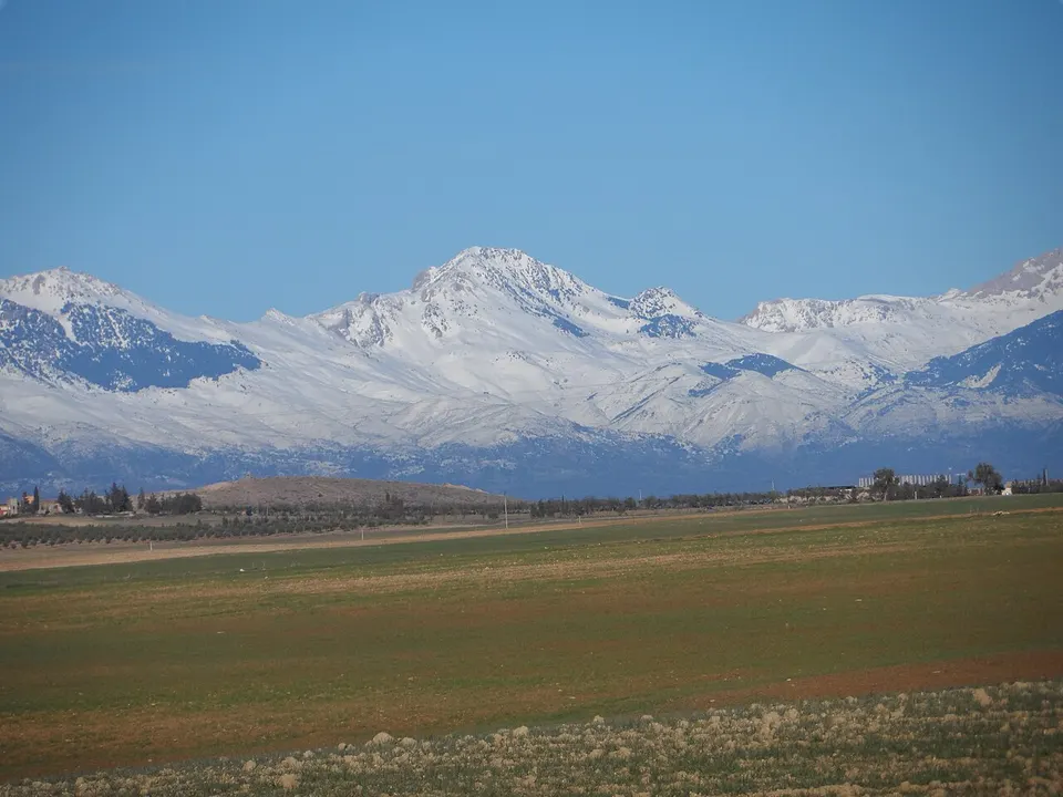 Snow-covered mountains above open fields — Bouira, Algeria