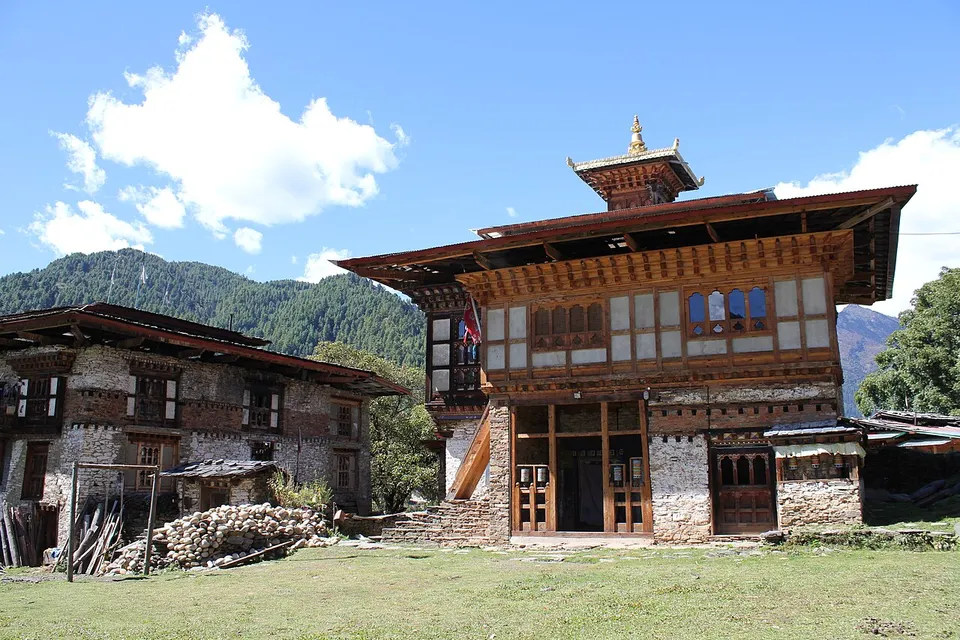 Village buildings beneath wooded mountains — Bumthang, Bhutan